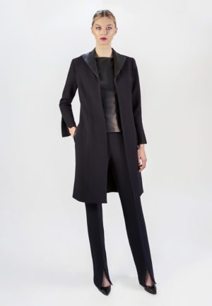 A woman in black coat and pants standing on white background.